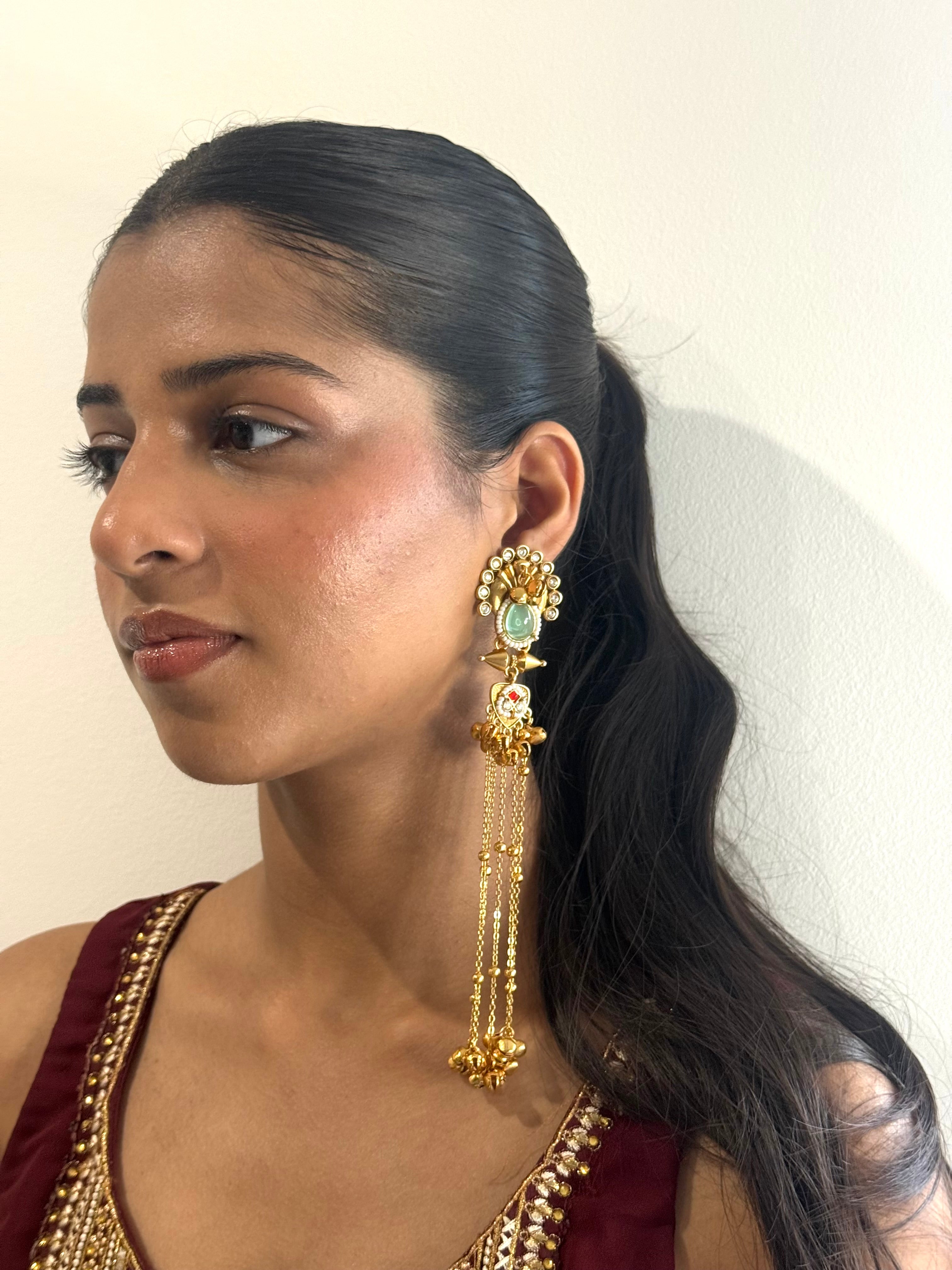 Woman wearing gold earrings with a plain background