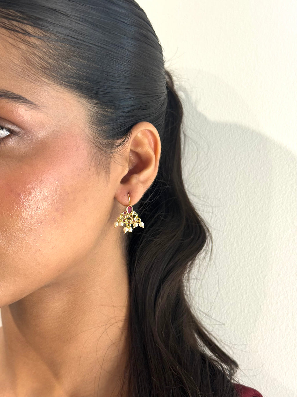 Close-up of a woman wearing a floral earring with a neutral background