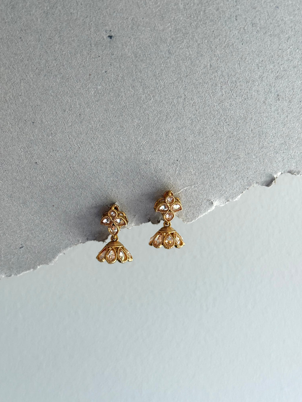 Gold earrings on a textured gray surface